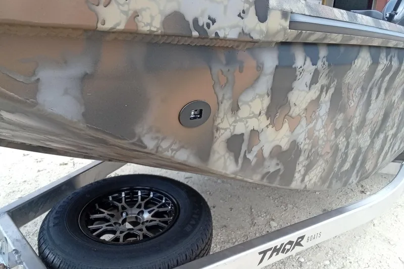 Slide: The Image of Camouflage-patterned 2026 Thor 1754 Timber Hammer boat on trailer with custom wheel. - 4
