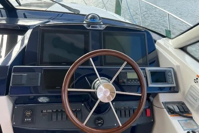 Slide: The Image of 2014 Tiara Yachts 3900 Coronet helm with modern navigation displays and wooden steering wheel. - 11
