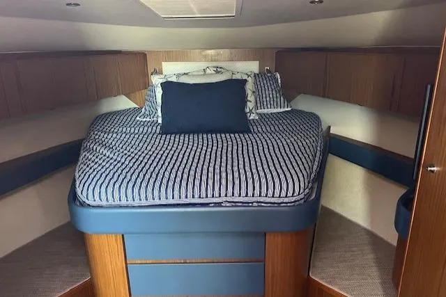 Slide: The Image of 2014 Tiara Yachts 3900 Coronet cabin with striped bedding and wooden interior. - 19