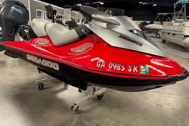 The Image of 2005 Sea-Doo Wake 155 jet ski in showroom, red and silver design, displayed on stand. - 1
