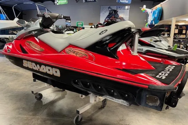 Slide: The Image of 2005 Sea-Doo Wake 155 jet ski in showroom, red and black design, side view. - 6