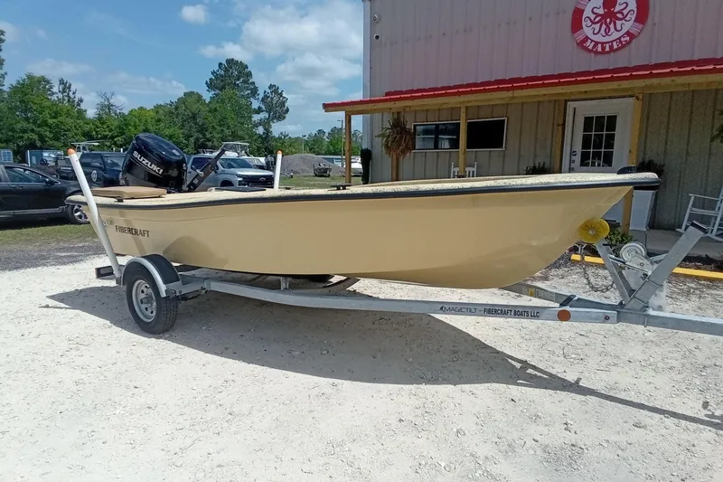 Slide: The Image of 2025 Fibercraft F16 boat on trailer, parked outside a building on a sunny day. - 12