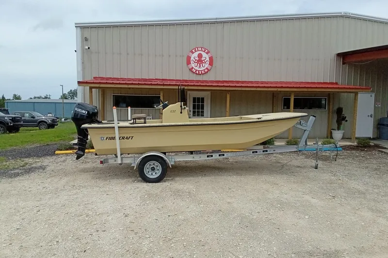 Slide: The Image of 2025 Fibercraft F17 boat on trailer outside a metal building with red roof. - 3