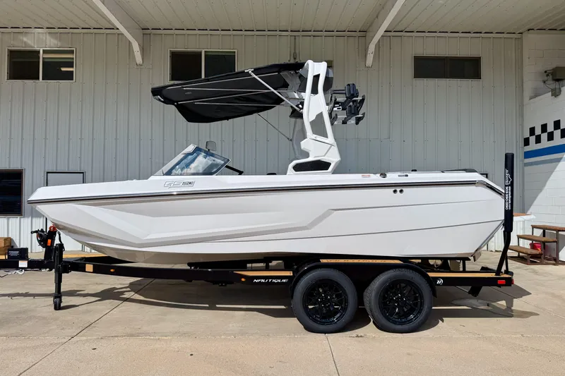 Slide: The Image of 2026 Nautique Super Air Nautique GS20 boat on trailer, parked outside a building. - 1