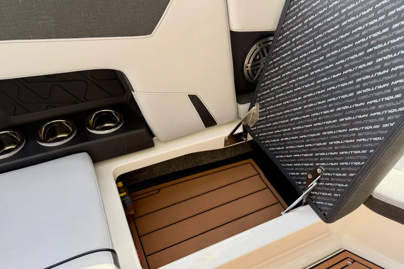 Slide: The Image of 2026 Nautique Super Air Nautique GS20 interior storage compartment with open hatch and cup holders. - 29