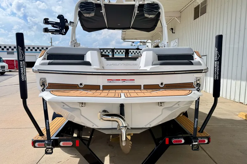 Slide: The Image of 2026 Nautique Super Air Nautique GS20 boat on trailer, rear view, in a marina setting. - 5