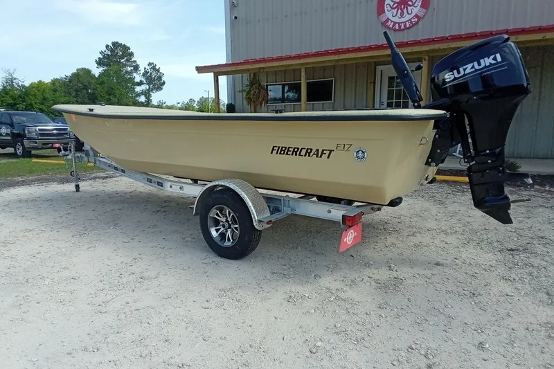 Slide: The Image of 2025 Fibercraft F17 boat on trailer with Suzuki outboard motor, parked outdoors. - 7