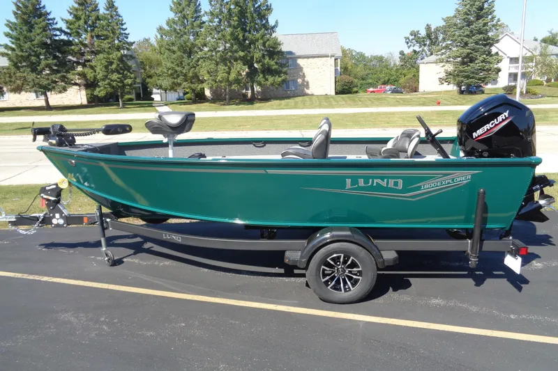 The Image of 2026 Lund 1800 Explorer Tiller boat on trailer, green exterior, parked outdoors. - 1