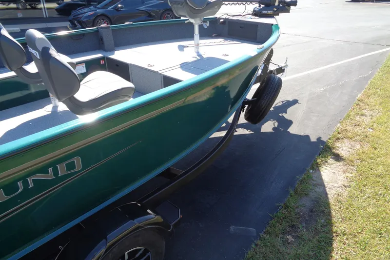 Slide: The Image of 2026 Lund 1800 Explorer Tiller boat on trailer, green exterior, parked on pavement. - 16