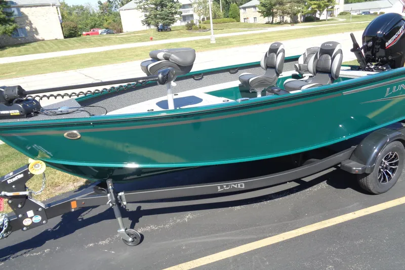 Slide: The Image of 2026 Lund 1800 Explorer Tiller boat on trailer, green exterior, parked outdoors. - 3