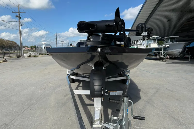 Slide: The Image of 2025 Xpress H20 Bass boat on trailer, featuring Minn Kota motor, parked outdoors. - 2