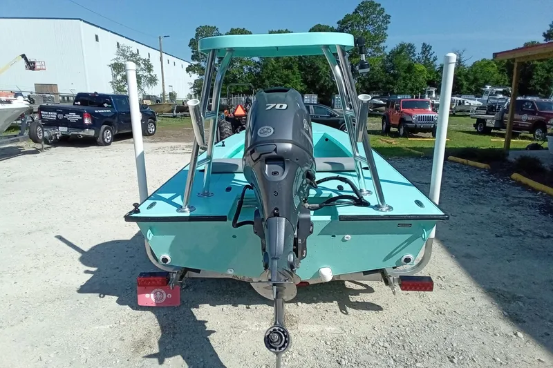 Slide: The Image of 2025 Cast & Blast 17CC Flats boat with outboard motor, parked outdoors. - 11