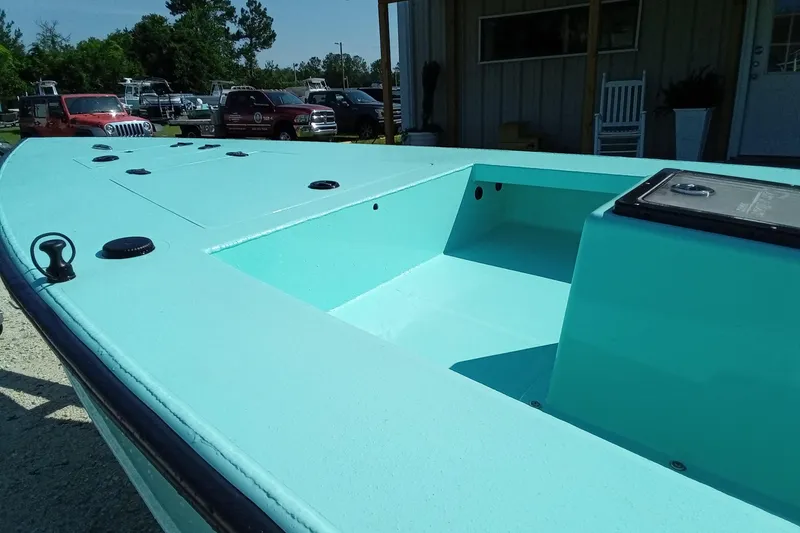 Slide: The Image of 2025 Cast & Blast 17CC Flats boat, turquoise deck, parked outdoors near vehicles. - 13