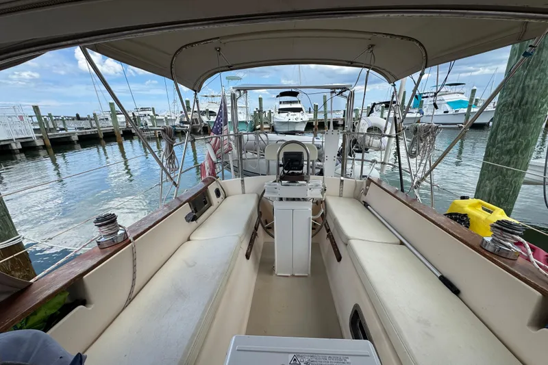 Slide: The Image of 1995 Island Packet 32 sailboat cockpit at marina, featuring seating and steering wheel. - 20