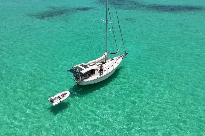 Slide: The Image of Sailboat Island Packet 32 (1995) anchored in clear turquoise water, with a small dinghy. - 3