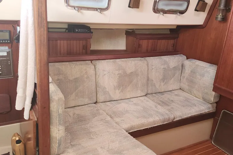 Slide: The Image of Interior of a 1995 Island Packet 32 sailboat with cushioned seating and wooden accents. - 32