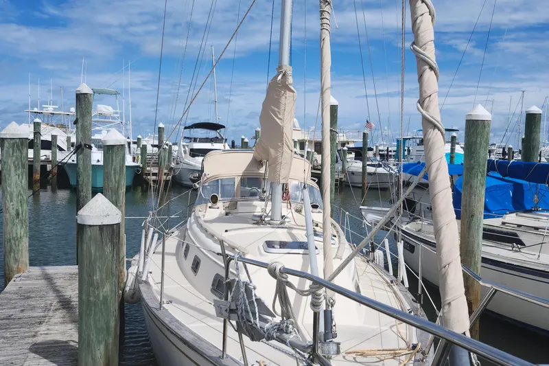 Slide: The Image of 1995 Island Packet 32 sailboat docked at a marina under a clear blue sky. - 7
