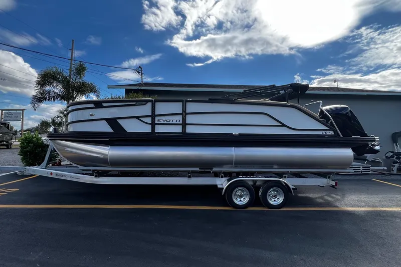 The Image of 2026 Evotti 521CS pontoon boat on trailer under a partly cloudy sky. - 0