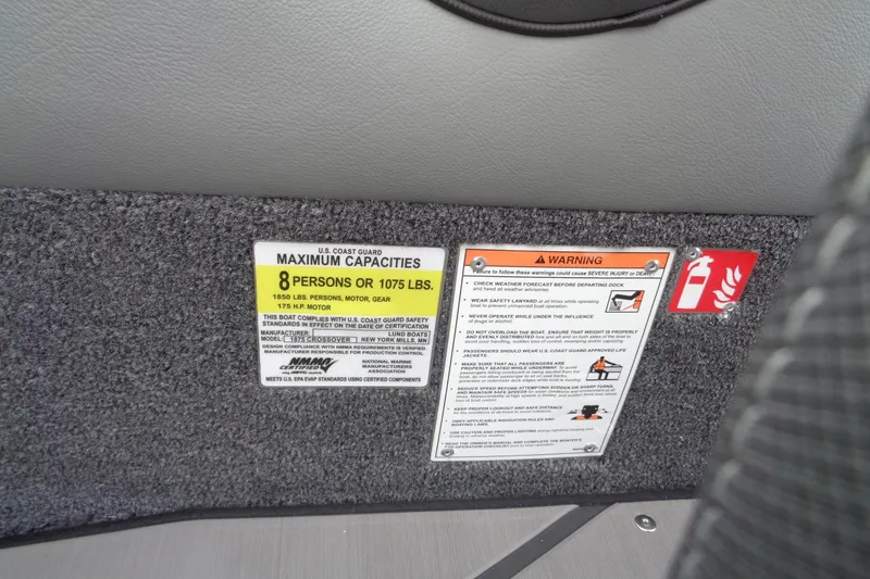 Slide: The Image of Capacity and safety warning labels on 2026 Lund 1875 Crossover XS boat interior. - 17