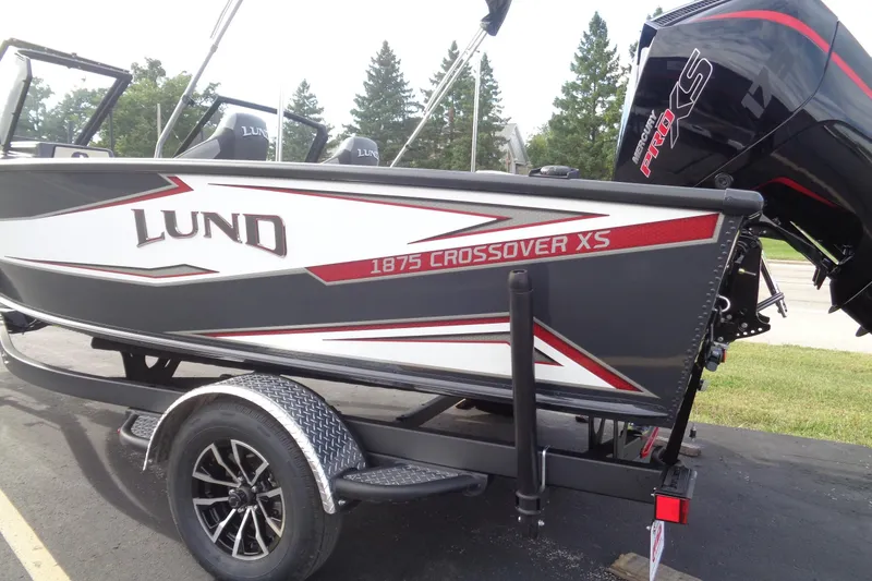 Slide: The Image of 2026 Lund 1875 Crossover XS boat on trailer, featuring sleek design and powerful engine. - 2