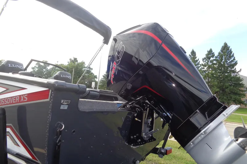 Slide: The Image of 2026 Lund 1875 Crossover XS boat with powerful outboard motor, parked outdoors. - 3