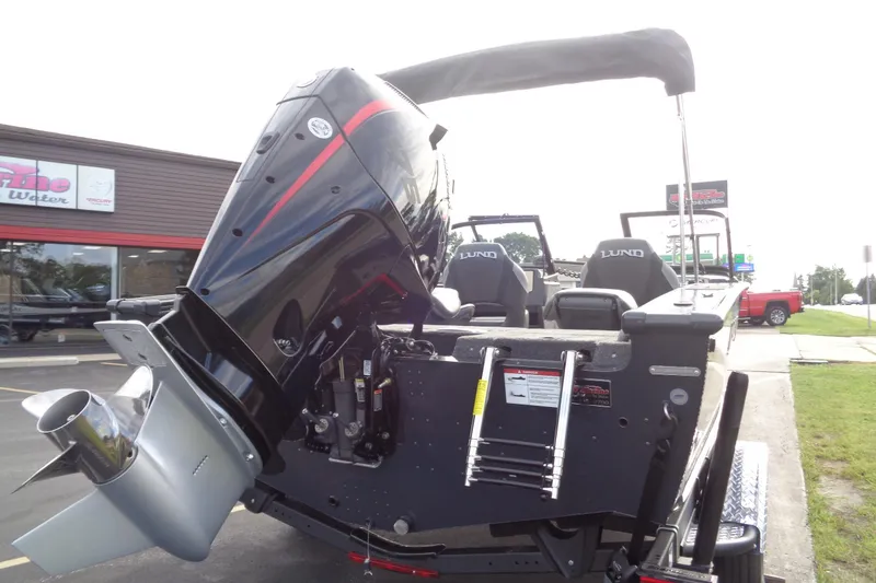 Slide: The Image of 2026 Lund 1875 Crossover XS boat with powerful outboard motor, parked outdoors. - 5