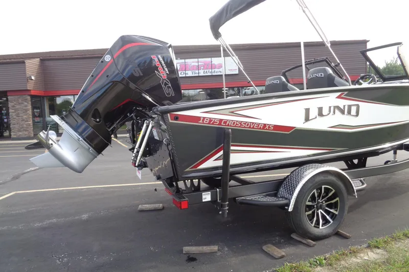 Slide: The Image of 2026 Lund 1875 Crossover XS boat on trailer, featuring powerful outboard motor. - 6