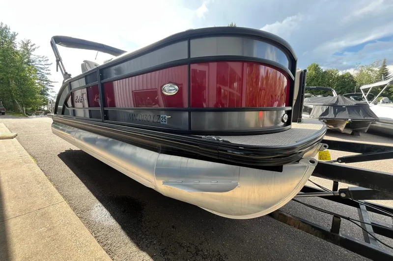 Slide: The Image of 2020 Barletta L23U pontoon boat on trailer, red and black design, parked outdoors. - 4