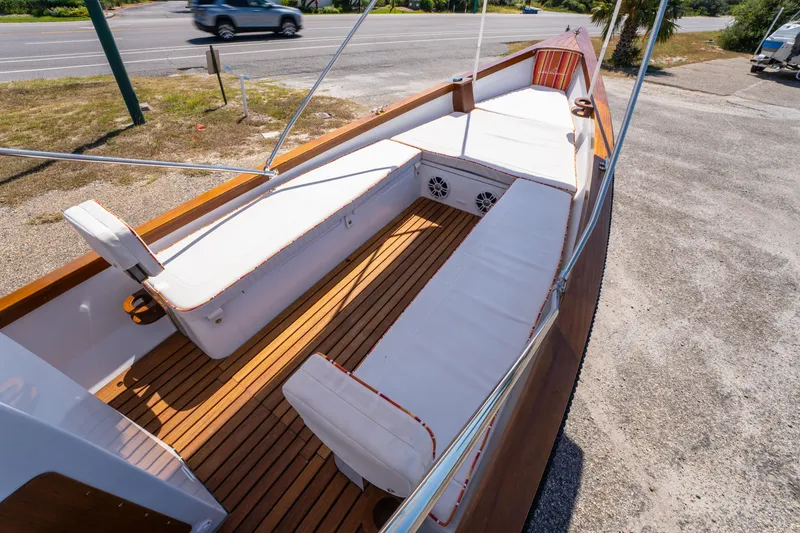 Slide: The Image of 2025 Caribiana Maracas 23 Skiff with white seating and wooden deck, parked near a road. - 13