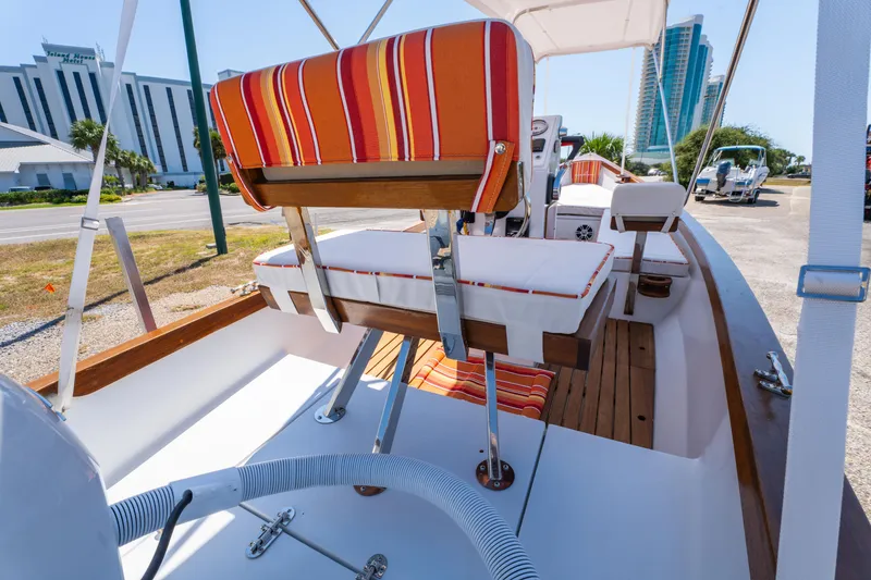 Slide: The Image of 2025 Caribiana Maracas 23 Skiff with striped seating, docked near modern buildings. - 21