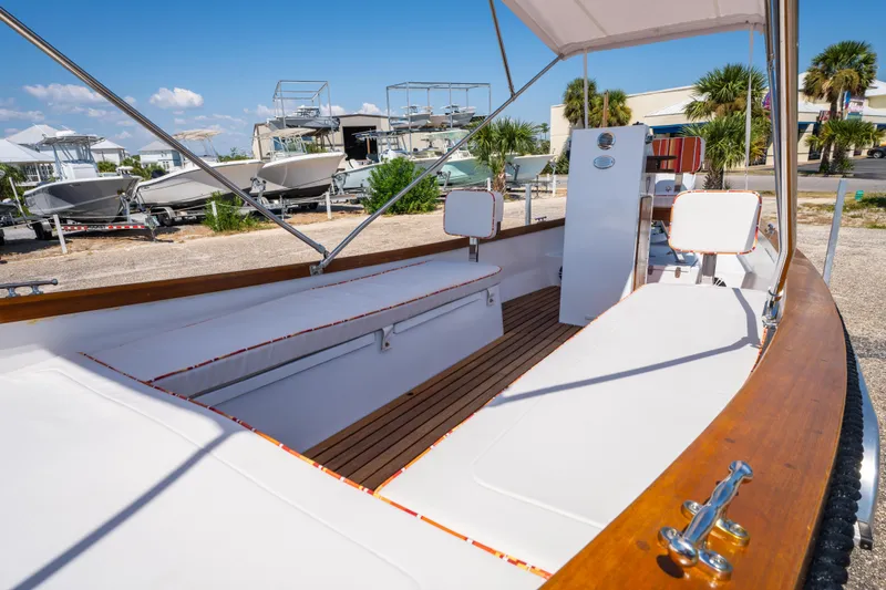 Slide: The Image of 2025 Caribiana Maracas 23 Skiff with white seating and wooden accents, docked outdoors. - 23