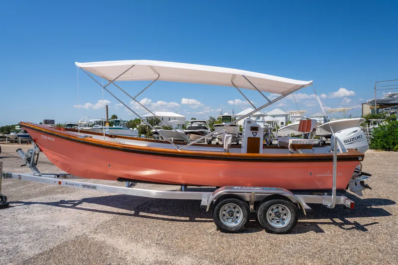 Slide: The Image of 2025 Caribiana Maracas 23 Skiff on trailer, featuring a canopy and Suzuki outboard motor. - 7