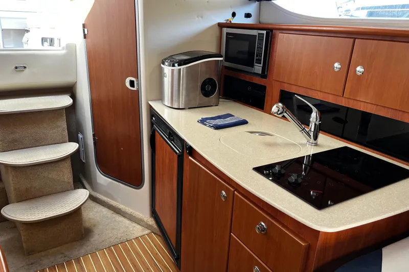 Slide: The Image of 2008 Bayliner 320 yacht interior with kitchenette, featuring stove, sink, and microwave. - 10