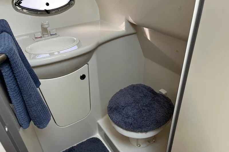Slide: The Image of 2008 Bayliner 320 boat bathroom with sink, toilet, and blue towels. - 14