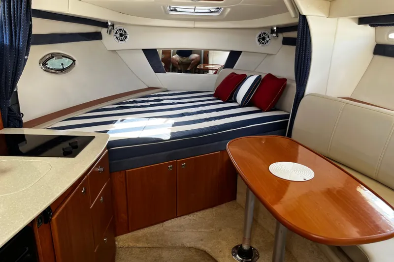 Slide: The Image of Interior of 2008 Bayliner 320 boat with striped bedding and wooden table. - 8