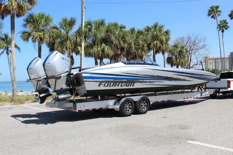 Slide: The Image of 2025 Fountain 34 Thundercat boat on trailer, parked near palm trees and ocean. - 8