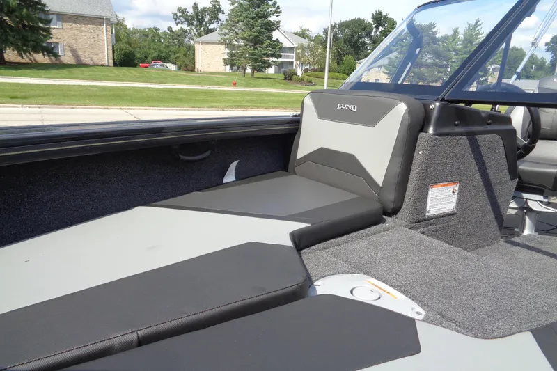 Slide: The Image of 2026 Lund 1875 Crossover XS boat interior with cushioned seating and windshield. - 10