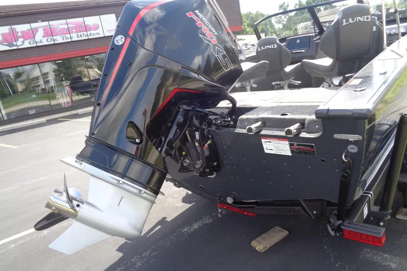 Slide: The Image of 2026 Lund 1875 Crossover XS boat with powerful outboard motor at dealership. - 6