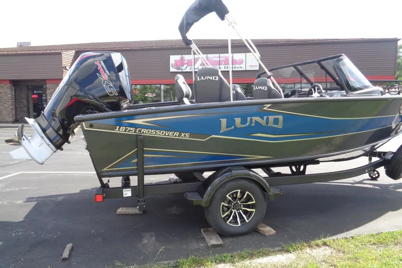 Slide: The Image of 2026 Lund 1875 Crossover XS boat on trailer, parked outside dealership. - 7