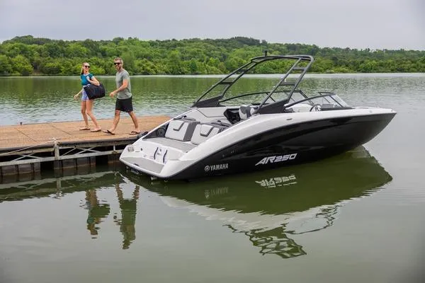 Slide: The Image of 2026 Yamaha AR250 boat docked on a serene lake with two people walking on the pier. - 10