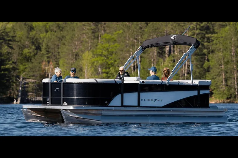 Slide: The Image of Manufacturer Provided Image: 2023 Crest CURRENT pontoon boat on a lake with passengers, surrounded by trees. - 2