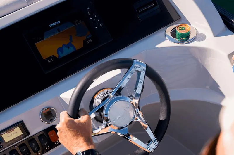 Slide: The Image of Manufacturer Provided Image: Person steering 2023 Crest CURRENT boat with navigation display and drink holder. - 3