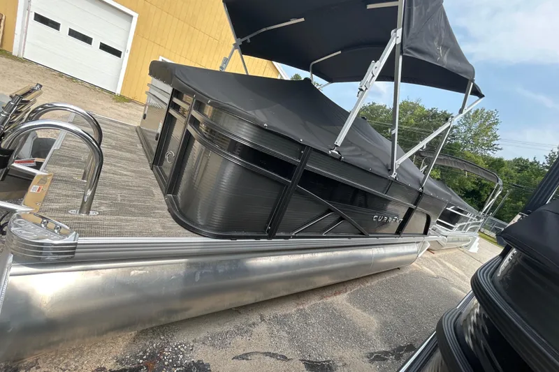 Slide: The Image of 2023 Crest Current pontoon boat with black canopy and sleek design on a trailer. - 5