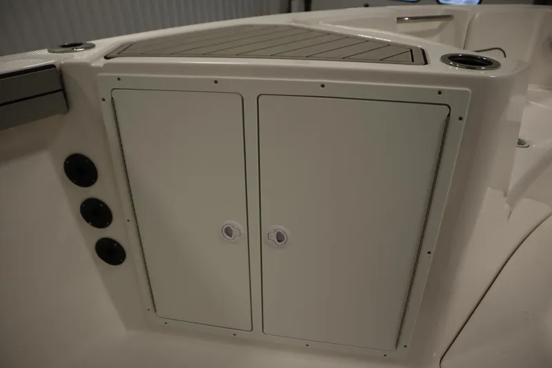 Slide: The Image of 2026 Yamaha Boats 220 FSH Sport storage compartment with cup holders and control panel. - 18
