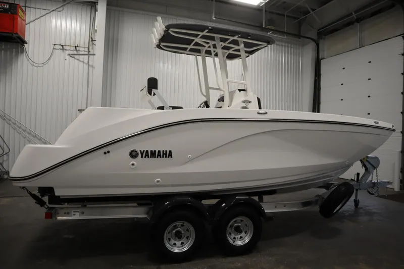 Slide: The Image of 2026 Yamaha Boats 220 FSH Sport in a showroom, side view. - 3