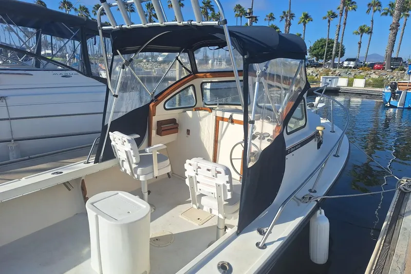 Slide: The Image of 1997 Steiger Craft 21 Block Island boat docked, featuring seating and canopy, with palm trees in background. - 8