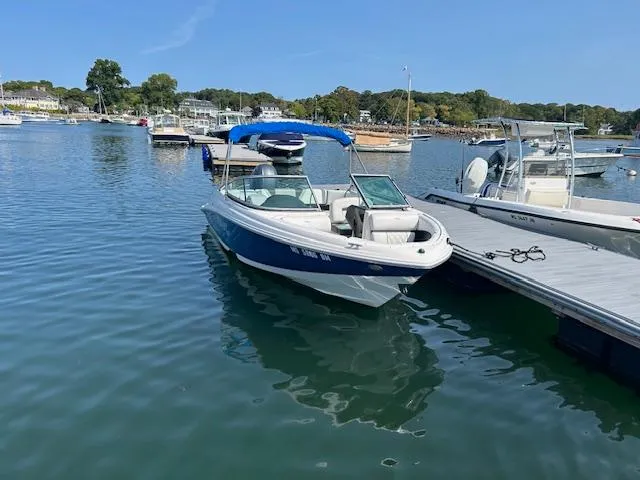 Slide: The Image of 2019 Regal 21 OBX boat docked in a serene marina setting. - 2