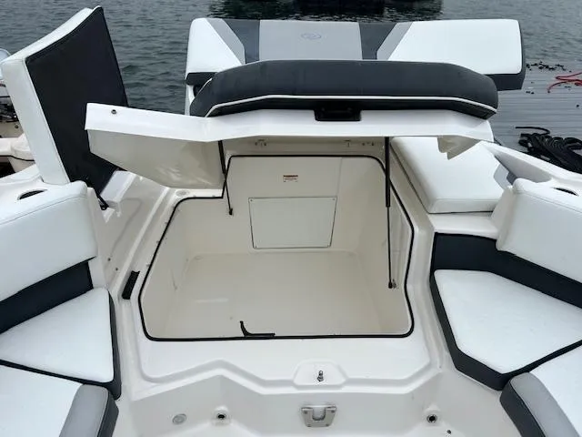 Slide: The Image of 2019 Regal 21 OBX boat with open storage compartment, white and gray seating, dockside view. - 6