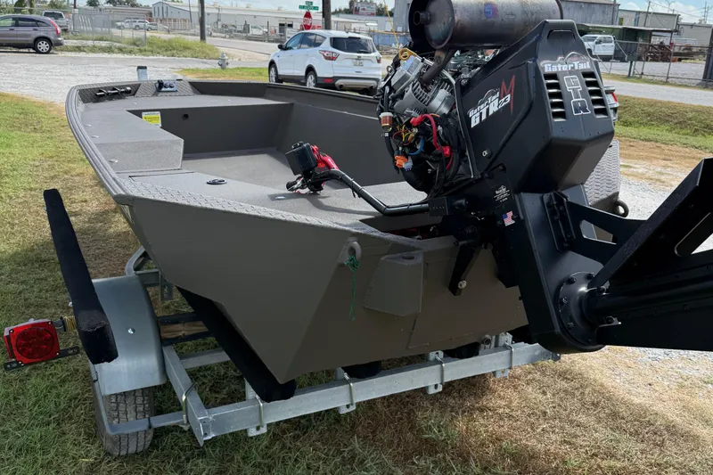 Slide: The Image of 2025 Alweld 1548 Invader boat on trailer with powerful motor, parked on grass. - 6