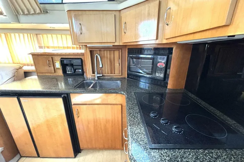 Slide: The Image of 2003 Carver 396 Motor Yacht kitchen with stove, microwave, sink, and wooden cabinets. - 35